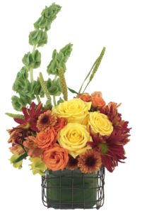 orange and yellow roses with assorted other fall flowers in cube vase