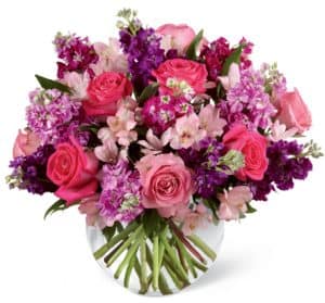 Hot pink and pink roses are brought together with purple, lavender and fuchsia stock stems accented with pink Peruvian lilies and lush greens to create a simply stunning flower arrangement. Presented in a clear glass bubble bowl vase,